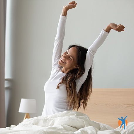 Happy woman streching in bed - good sleep is a great remedy for bad neck pain