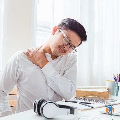 Muscle pain causes Man at computer holding his neck in pain - learn about the causes of muscle pain