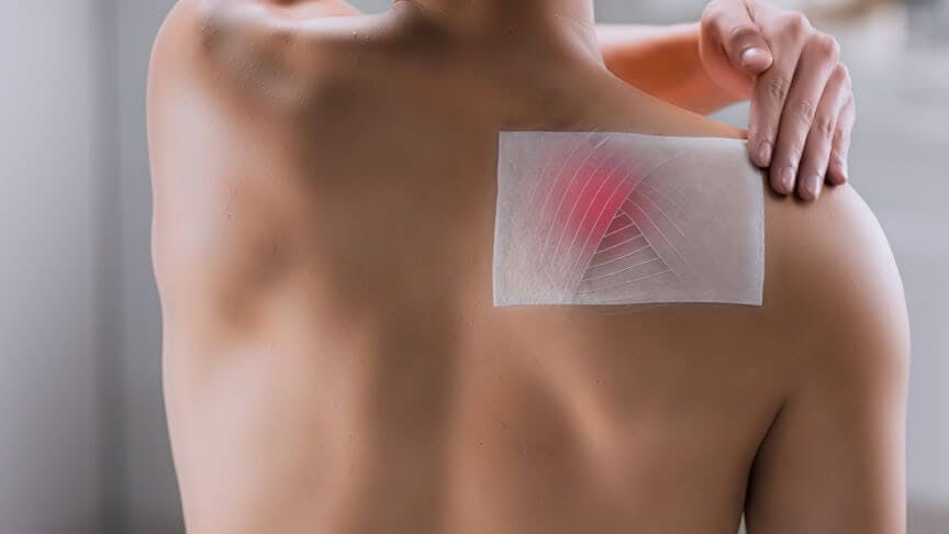 Man applying Voltarol patch on shoulder Man applying Voltarol patch on shoulder