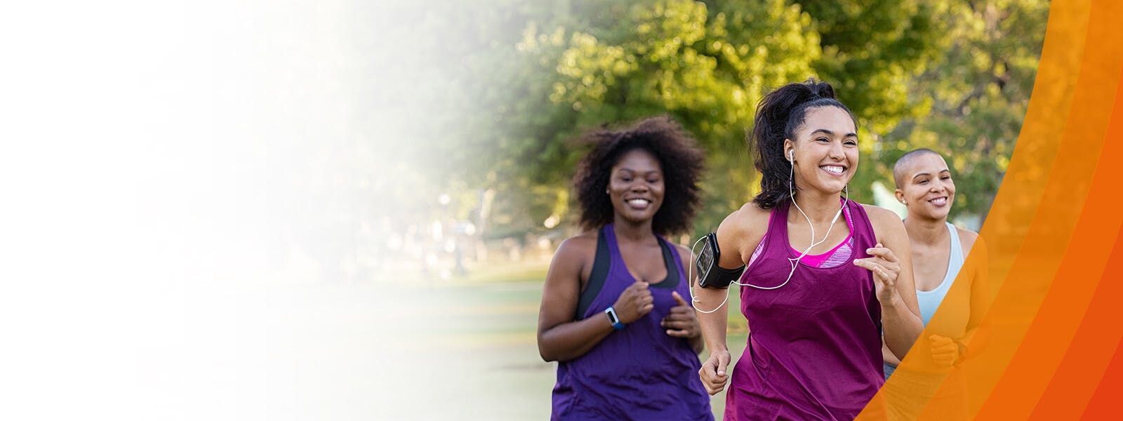 Three people running outside, they are smiling.