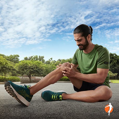 Man siting on the pavement holding his knee after a run session