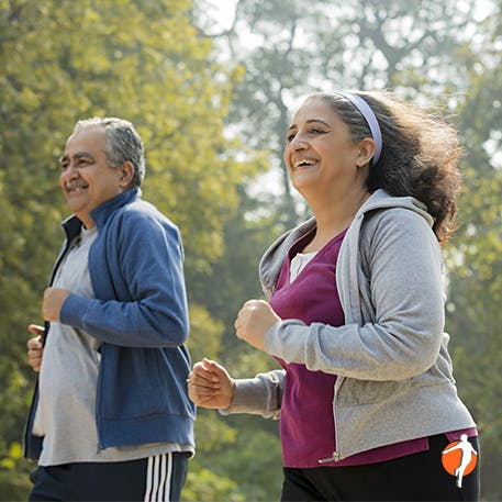 Elderly middle age couple running trough the forest