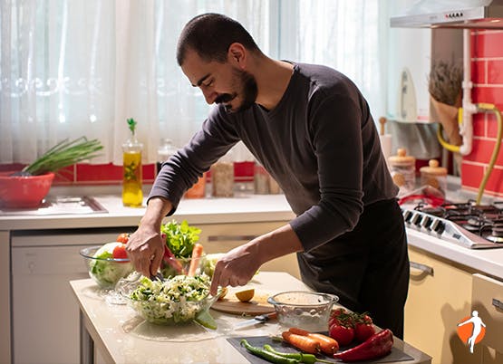 Man preparing healthy salad in his kitchen at home