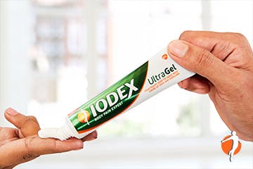 Person squeezing tube of Iodex UltraGel into hand