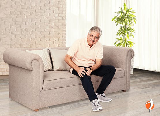 A man sitting on couch with knee pain