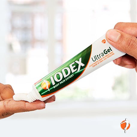A person squeezing a tube of Iodex UltraGel