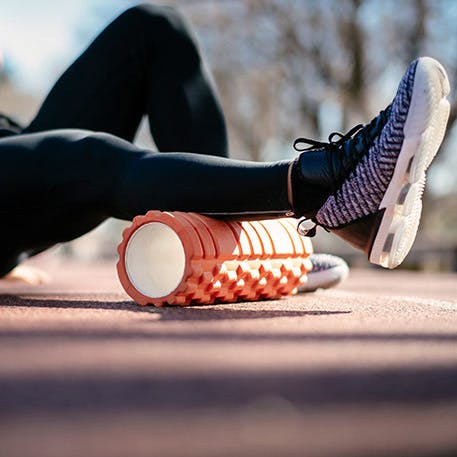 A runner using a foam roller on calf muscle