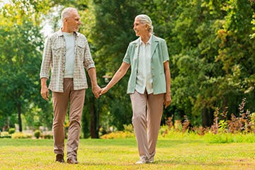 Taking a walk Older couple walking through a park holding hands