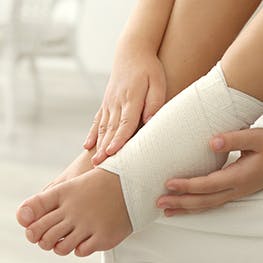 Person with their ankle wrapped from a sprain Person with their ankle wrapped from a sprain