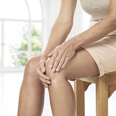 Woman experiences knee pain sitting on chair