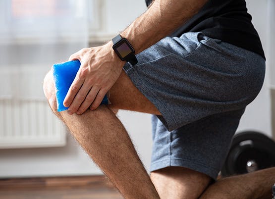 Man uses ice pack on knee pain as part of RICE method Man uses ice pack on knee pain as part of RICE method