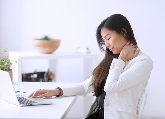 Woman at a computer holding her neck Woman at a computer holding her neck