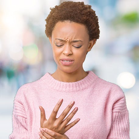 Woman outdoors holding her wrist in discomfort Woman outdoors holding her wrist in discomfort