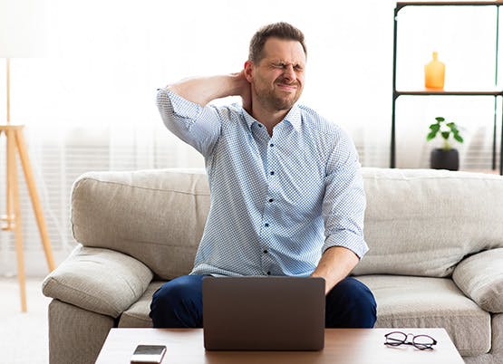 A man with a laptop working from home and neck pain 