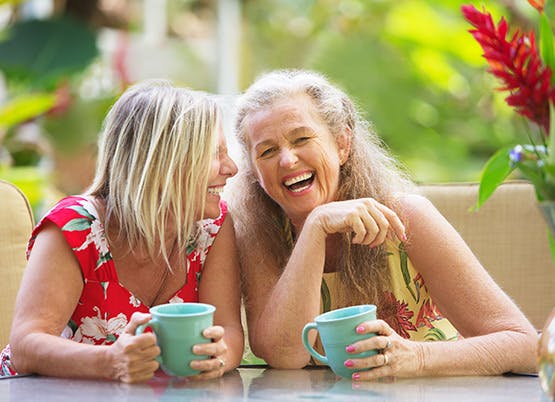 Two women relaxing and laughing over a cup of tea Two women relaxing and laughing over a cup of tea
