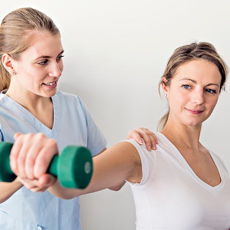 Woman with physical therapist doing a shoulder exercise Woman with physical therapist doing a shoulder exercise