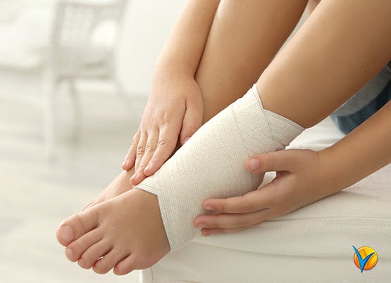 Woman compresses ankle pain with bandage as part of RICE method
