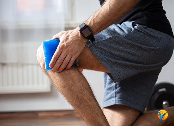 Man uses ice pack on knee pain as part of RICE method