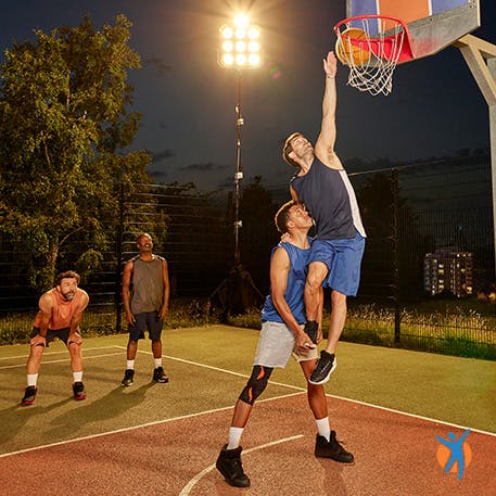 Un homme aide un ami à porter une attelle de basket-ball au niveau du genou.