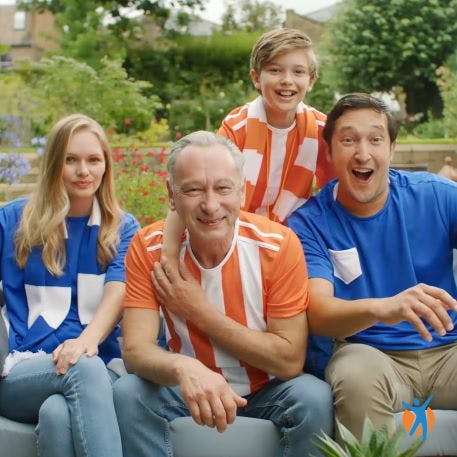 Heureuse famille de trois générations regardant un match de football à l'extérieur