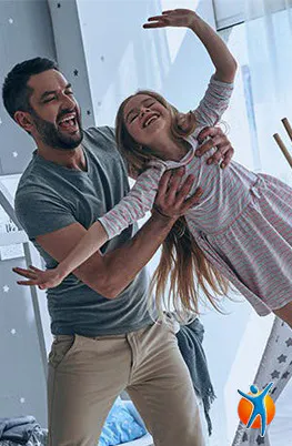 Homme soulève joyeusement fille en robe rose près fenêtre