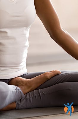 Mulher pratica posição de yoga sentada.