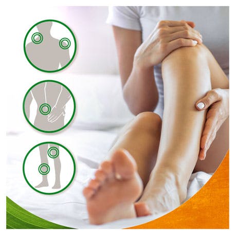 Mulher sentada na cama a aplicar gel de arnica nas pernas Mulher sentada na cama a aplicar gel de arnica nas pernas