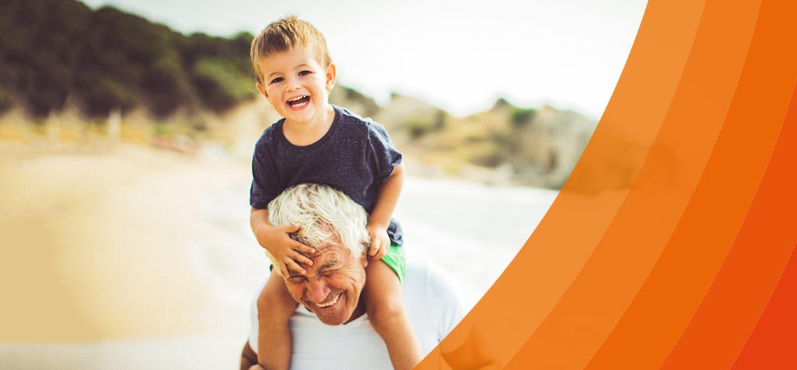 An elderly man with a young boy on his shoulders at the beach - explore the Voltarol range