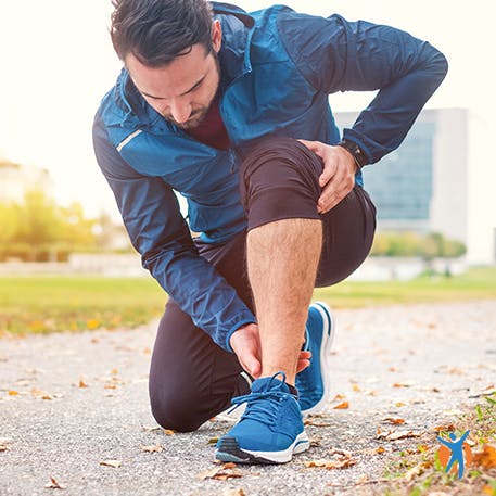 Man sitting in the road holding his calf due to heel and angle pain