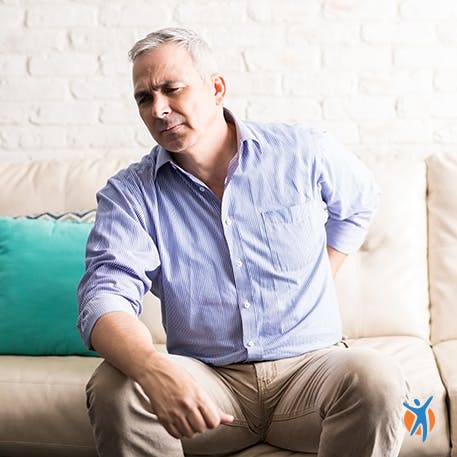 Back muscle pain from sleeping Woman in bed holding her back - lack of sleep is a main cause of muscle pain