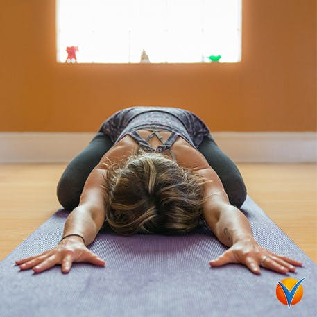 En kvinna i barnets position yogar för att sträcka ut ryggen