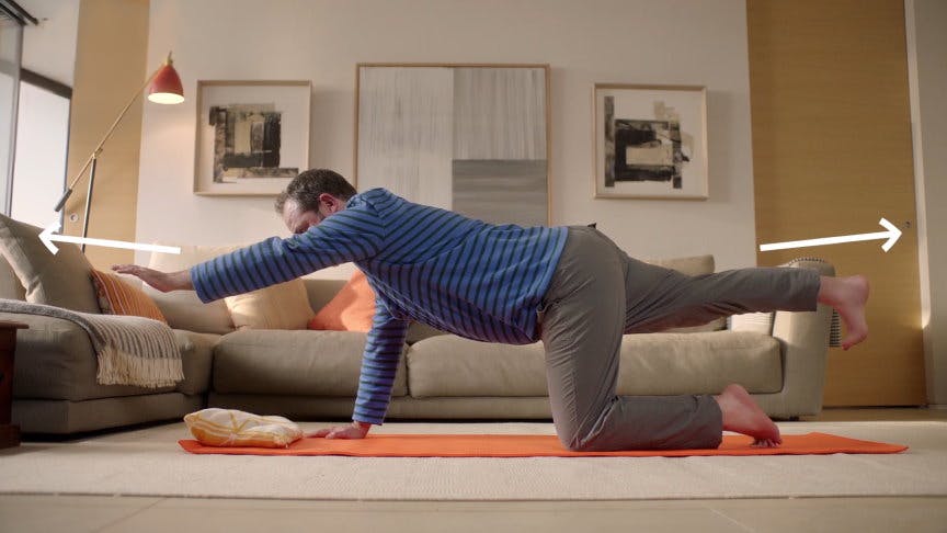 Man i medelålder utövar ryggövningar på yogamatta i sitt vardagsrum