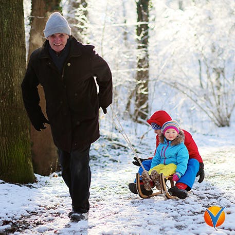 En man drar sin son på en släde i snön utan ryggsmärtor