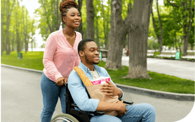 Woman pushing man in wheelchair with groceries