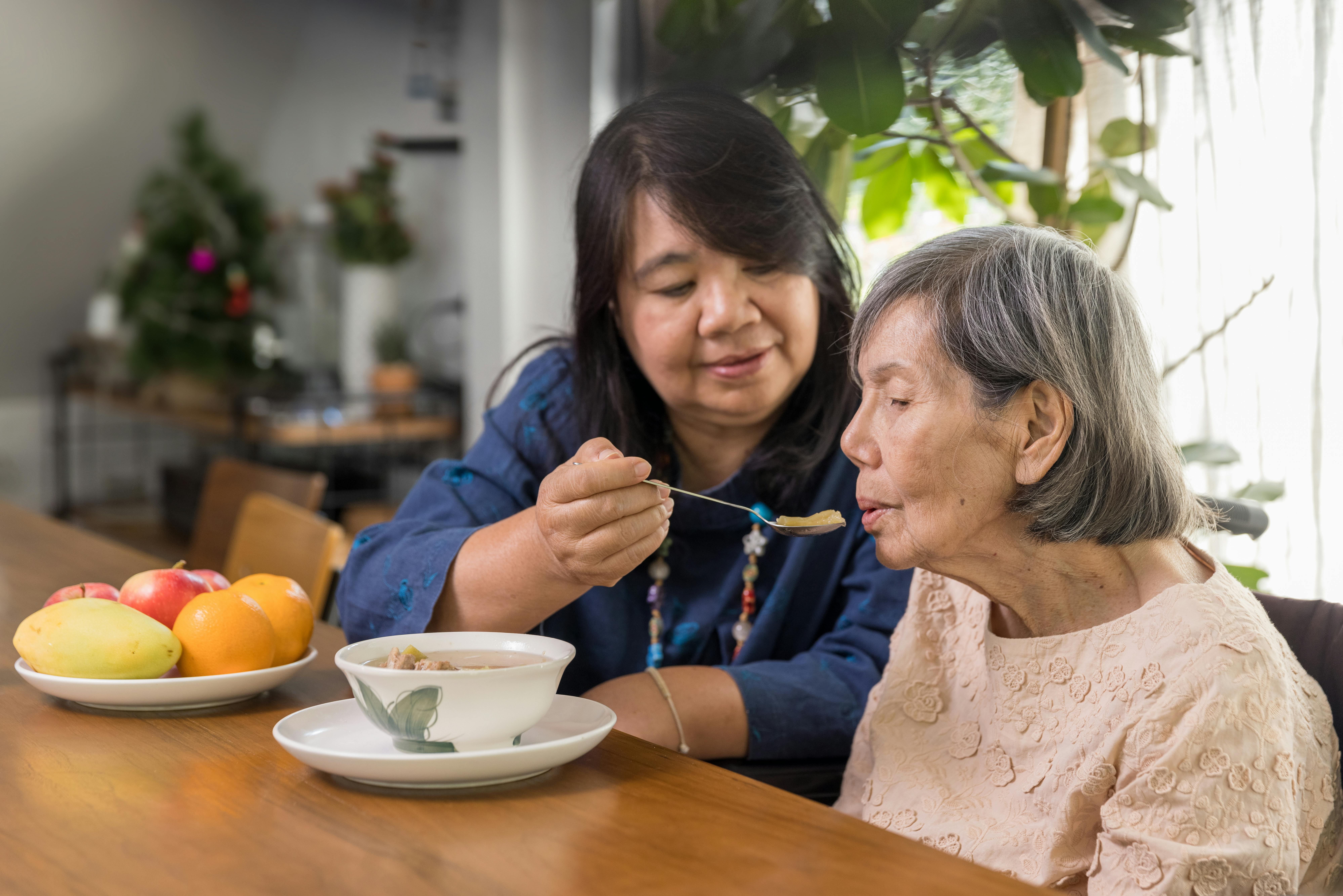 A caregiver feeds her patient soup