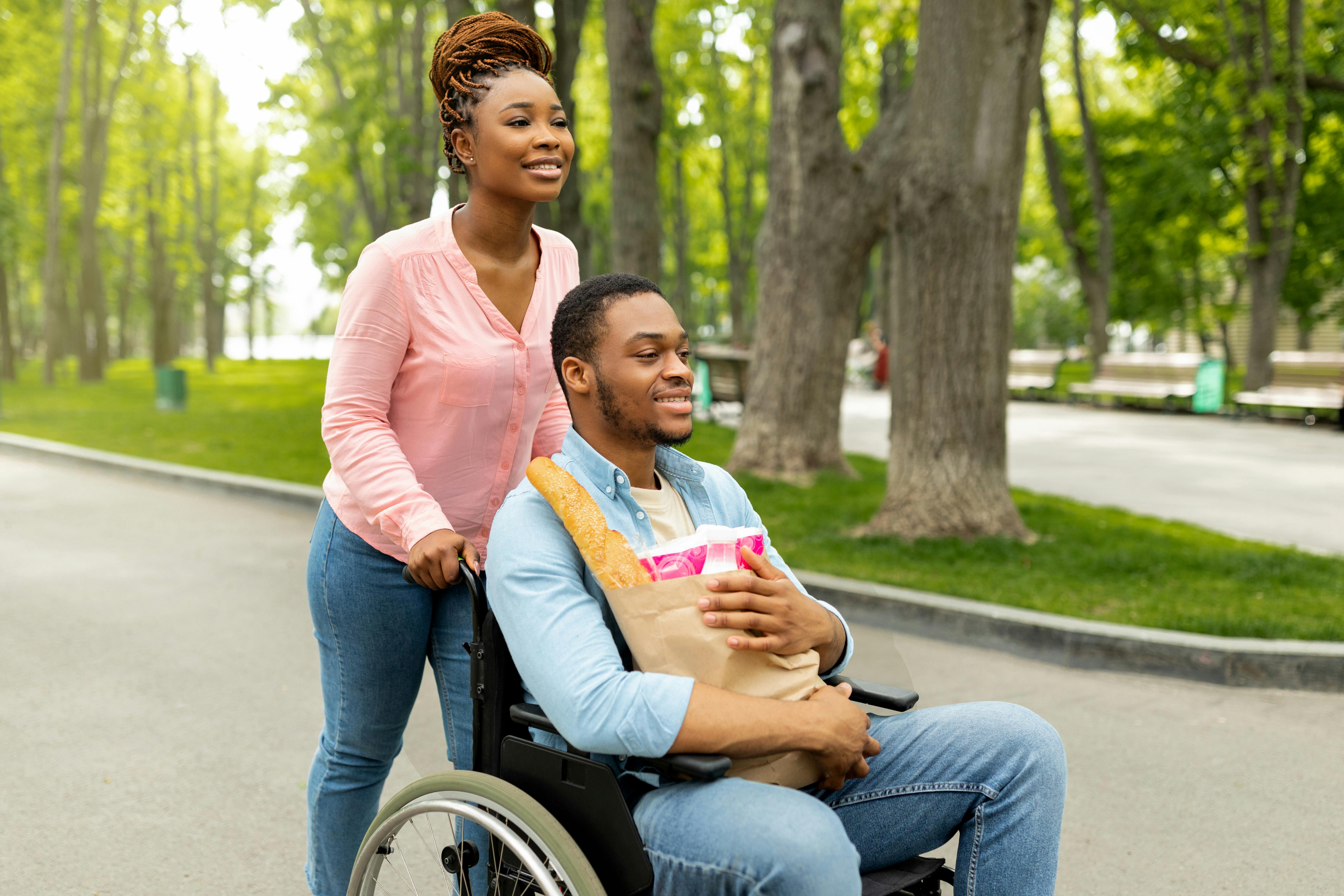 Woman pushing her spouse in his wheelchair outside