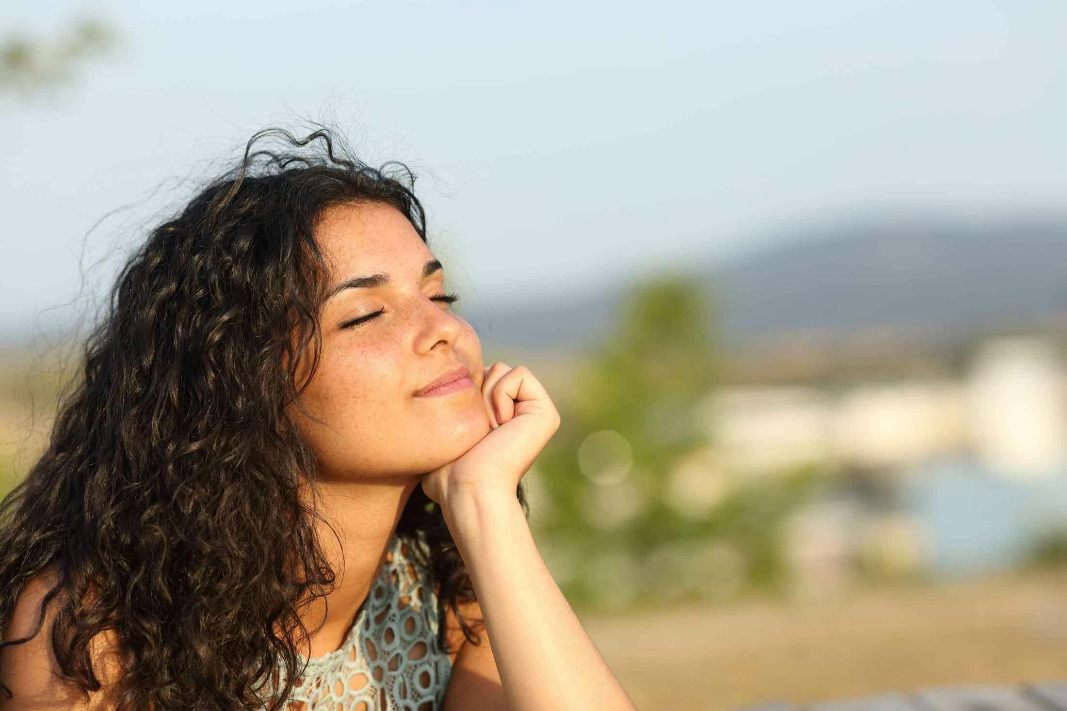 Young woman with eyes closed practicing mindfulness in the sunshine