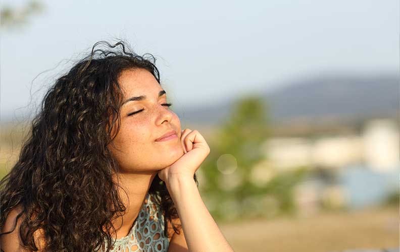 Young woman with eyes closed practicing mindfulness in the sunshine