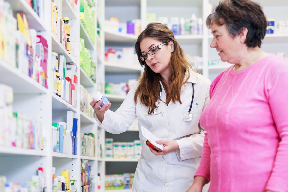 Pharmacist and consumer discussing medication in pharmacy aisle