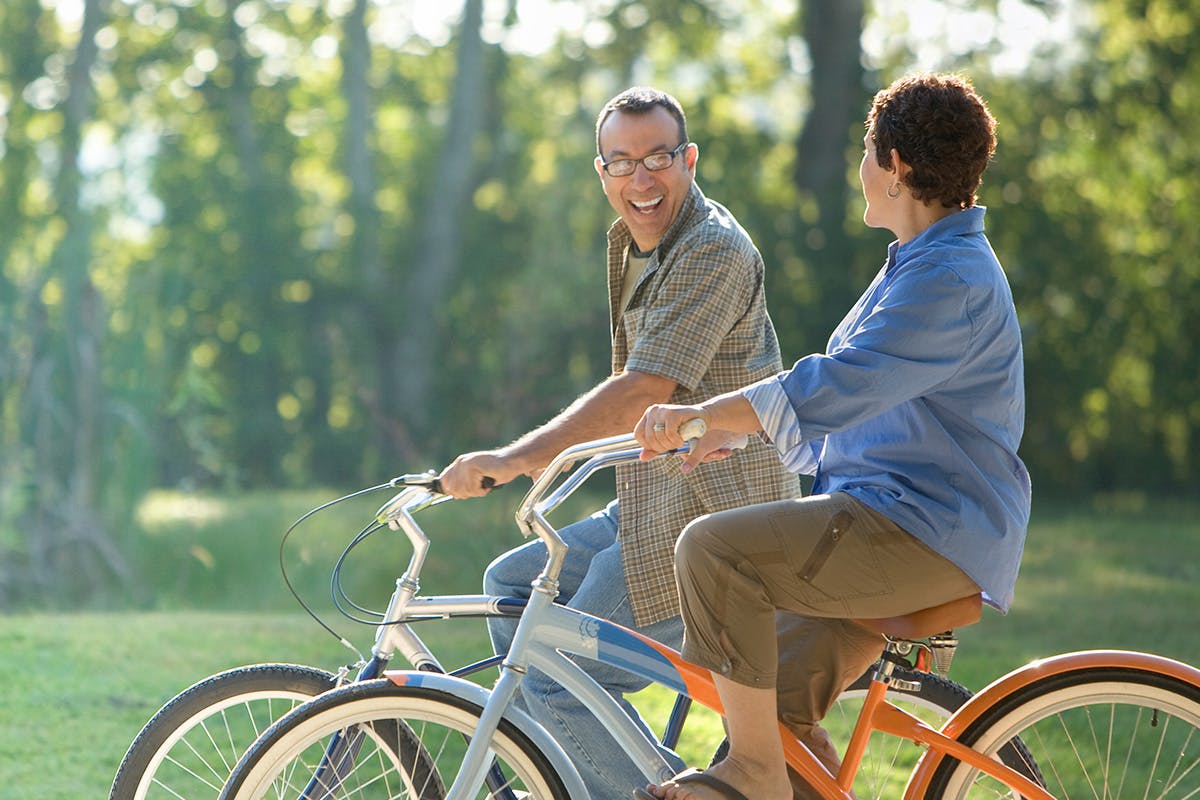 A couple riding their bikes with trees in the background