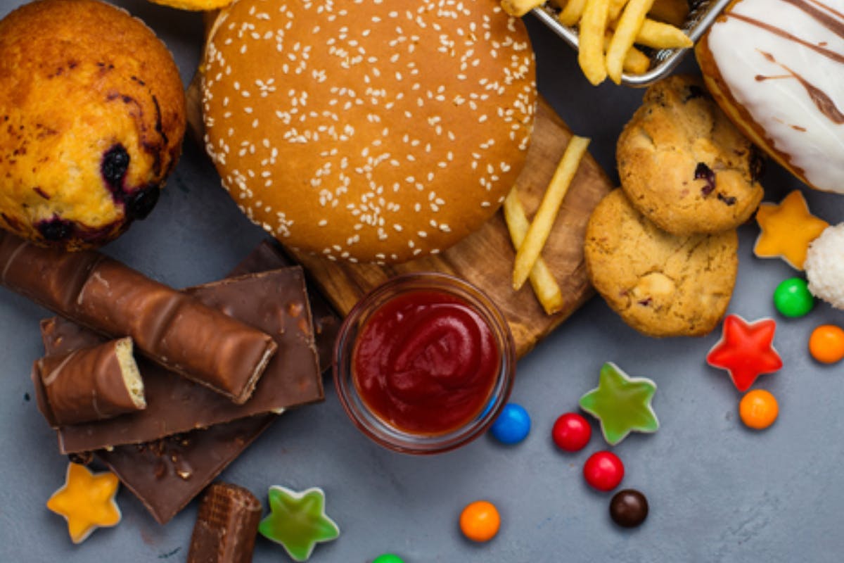 Food spread with hamburgers, French fries, candy, cookies, and other unhealthy foods