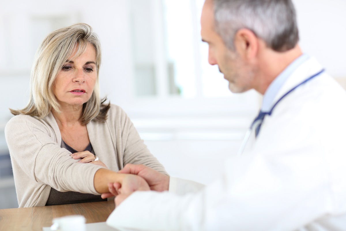 Woman consulting with doctor about elbow pain.