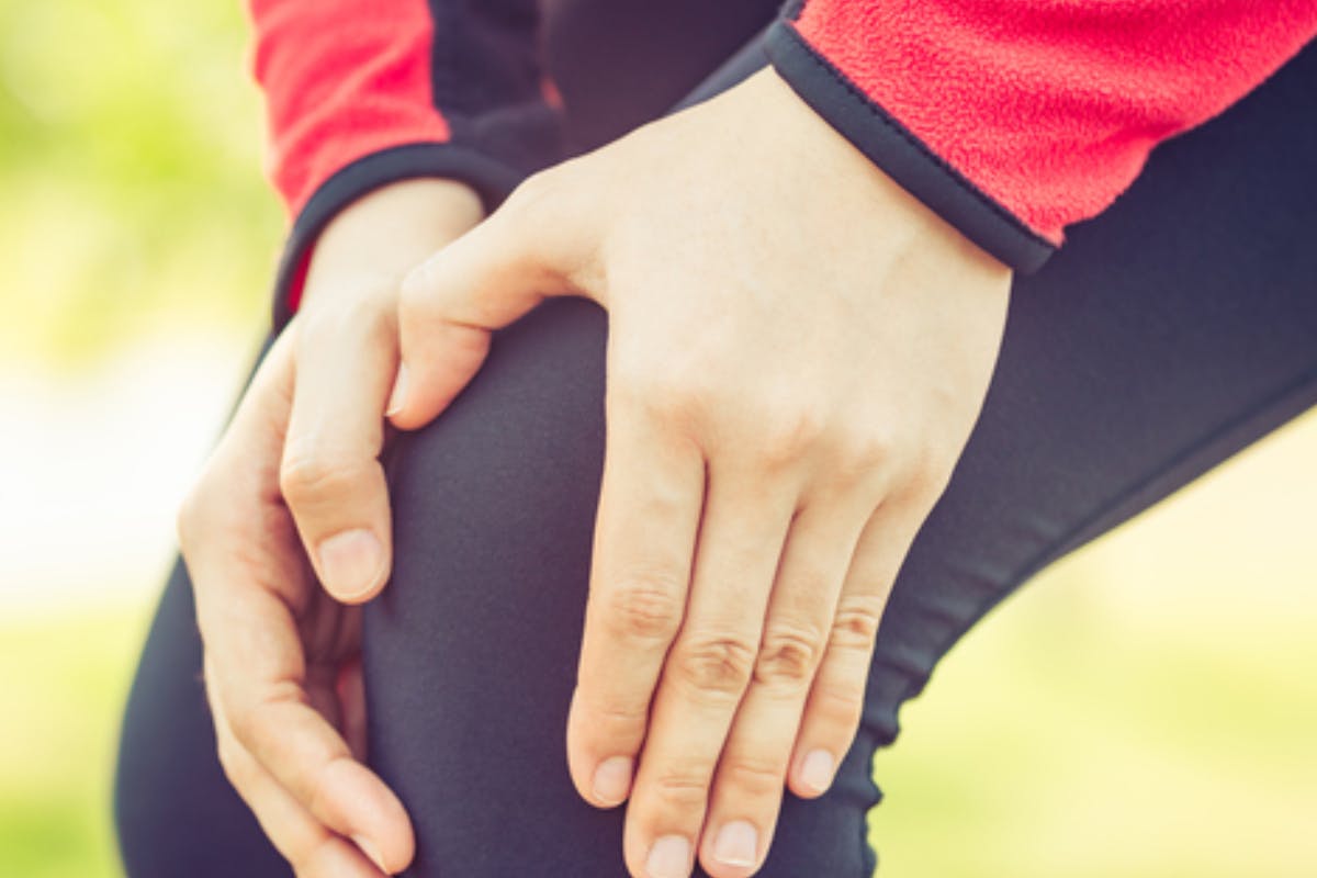 Senior woman sitting on her couch holding her painful knee