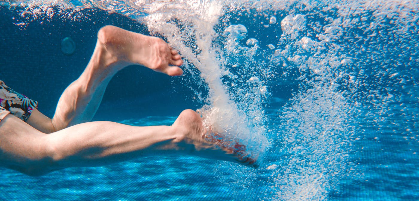 Close-up of man’s legs kicking in pool