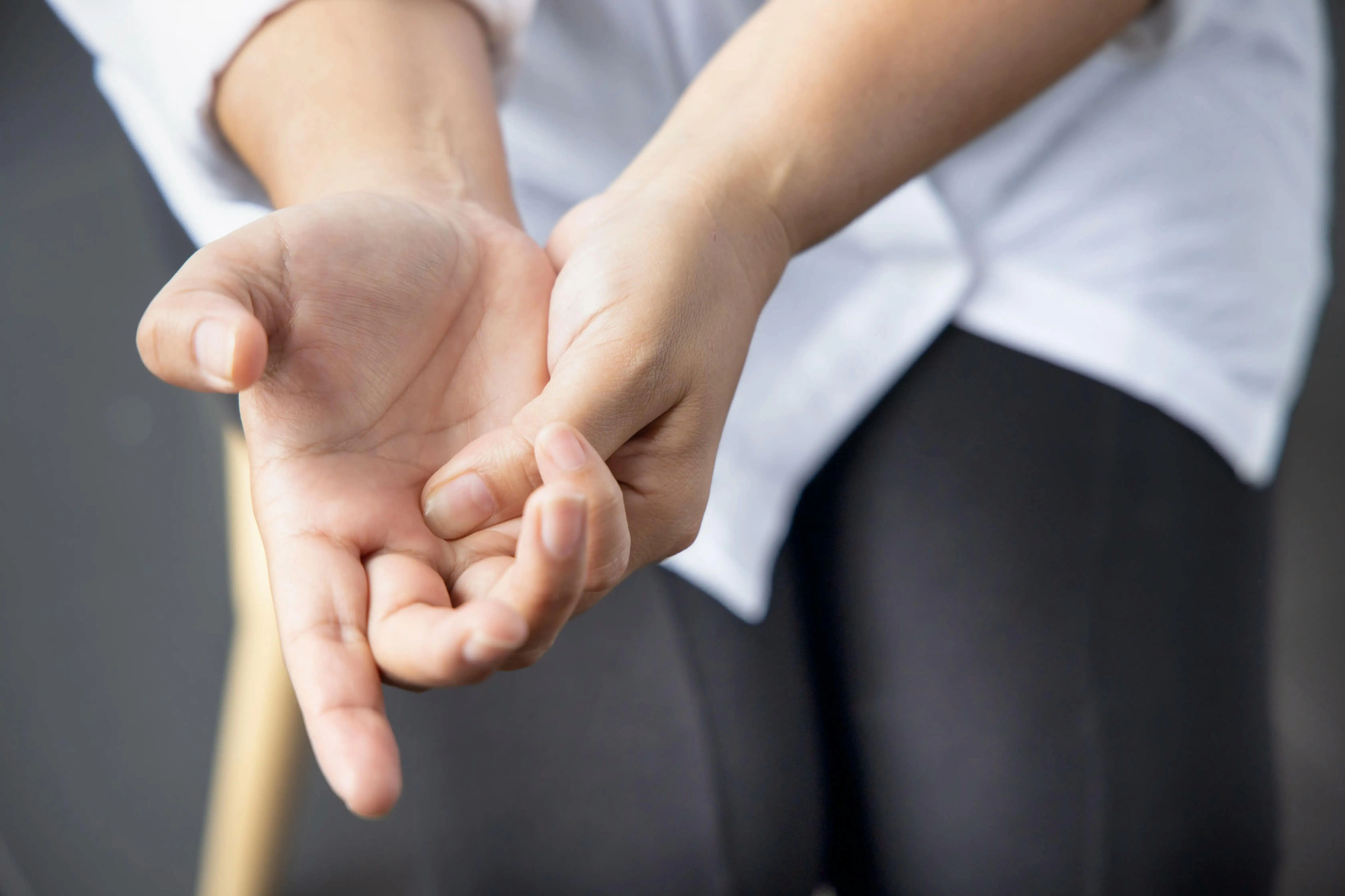 Person experiencing trigger finger holds their hand to relieve pain
