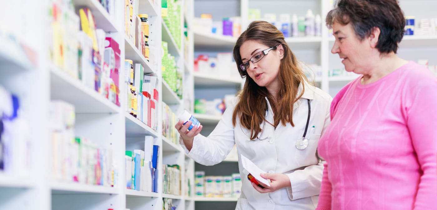Pharmacist and consumer discussing medication in pharmacy aisle