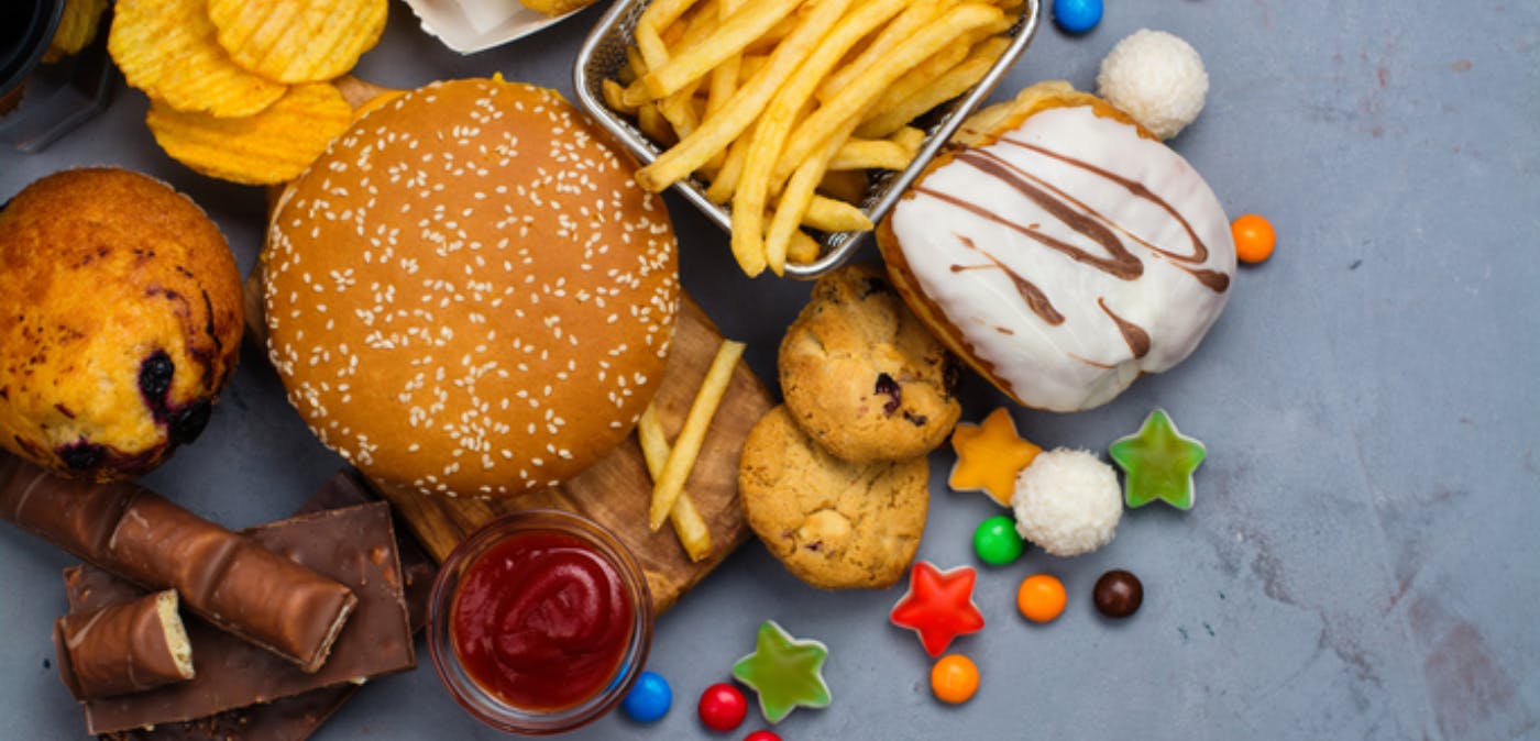 Food spread with hamburgers, French fries, candy, cookies, and other unhealthy foods