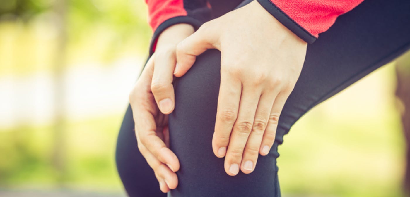 Close-up of female runner with her hands placed on her painful knee