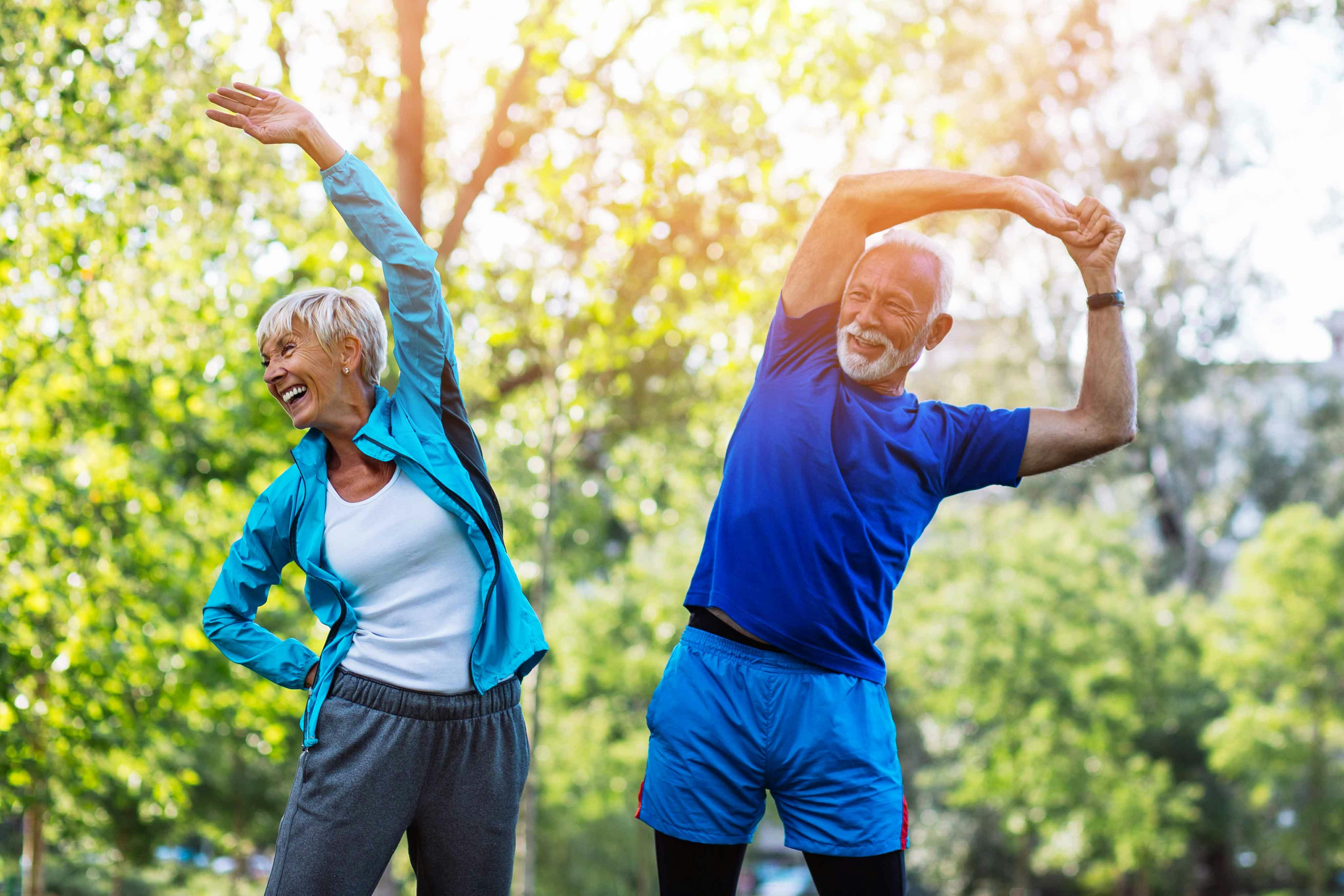 Older man and woman stretching outside together