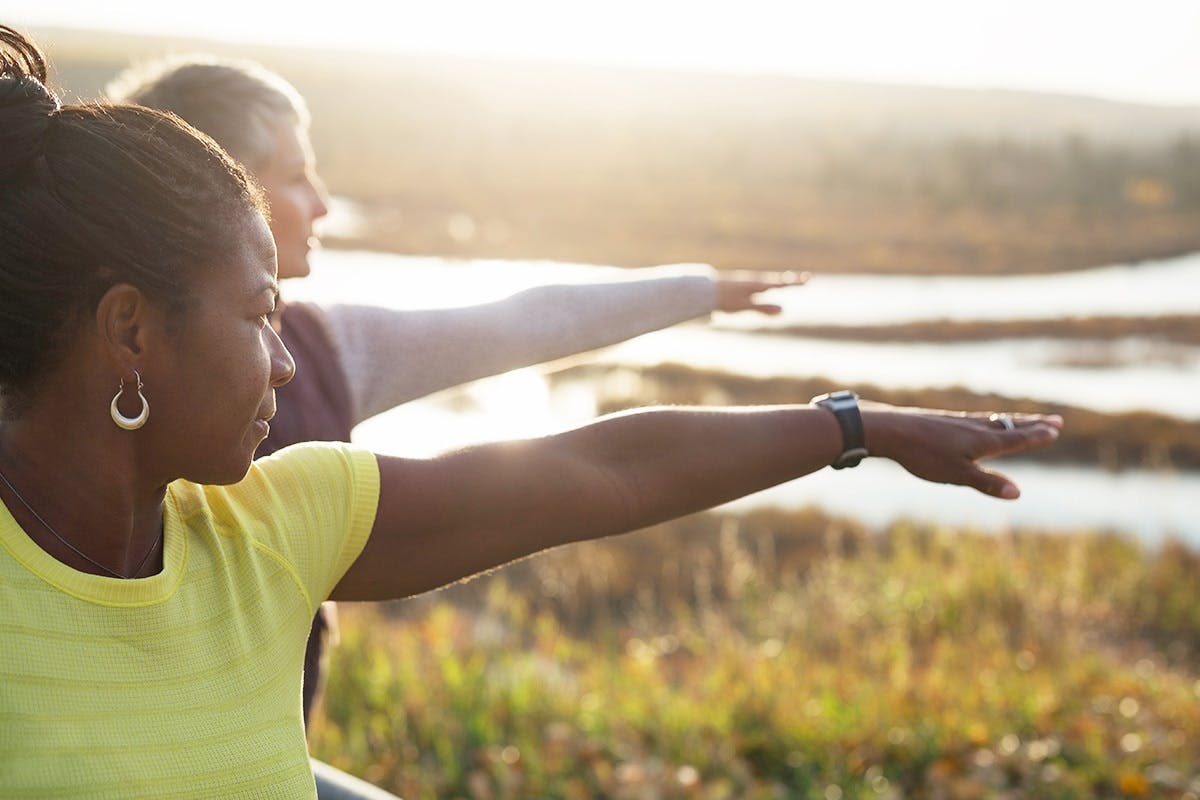 Two person stretching on hill